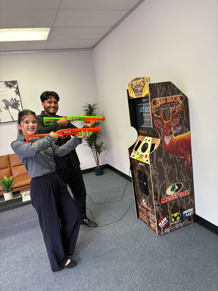 Palm City Management team members enjoying the office arcade game, showing the fun work culture